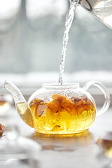A delicious herbal tea from rose petals, cozy atmosphere. White floral drink in a transparent glass. Flowing liquid.