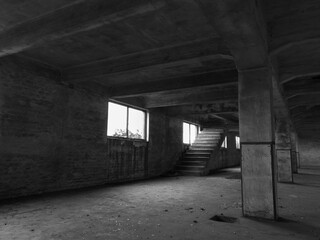 Interior of an empty deserted messy industrial warehouse, urban exploration of an abandoned building with broken windows and large pillars