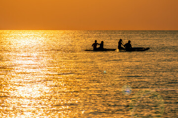 Couples Enjoy Golder Sunset while Kayaking out on the Sea.