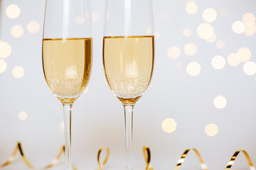 Two glasses of champagne with lights and ribbons on a white background holiday