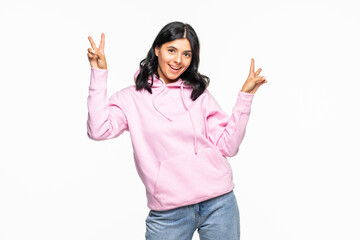 Portrait of a cheerful young woman showing peace gesture wearing hoodie standing isolated over...