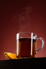 Glass mug of black hot tea with lemon and steam. View from below