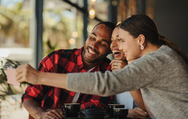 Friends at cafe capturing a selfie on phone