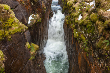 Obraz premium The Pont d’Espagne bridge on the river Gave du Marcadau, Cauterets. Beneath the bridge the river Gave du Marcadau tries to finds it way through a narrow gorge, creating a powerful rapid / waterfall.