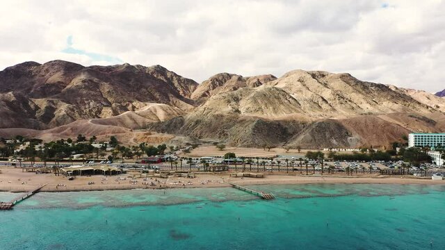 Aerial view of Eilat's Coral Beach Nature Reserve and Conservation area coastline. Pulling back and revealing the Eilat mountains and some hotels.


