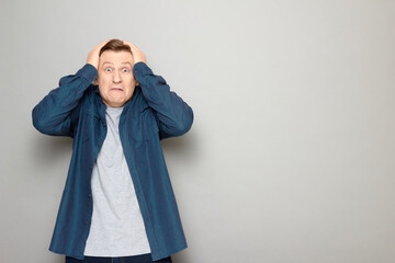 Portrait of shocked mature man clutching his head with both hands