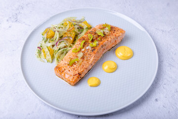 Fried salmon with fennel and orange salad with hollandaise sauce. Garnished with leeks. French dish. Close-up.