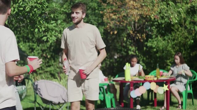 Young Man Pours Charcoal Lighter Fluid To Bbq Grill