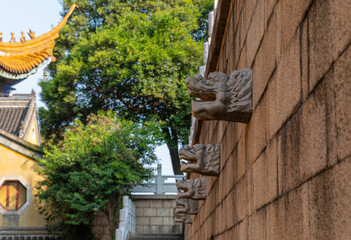 Vivid stone dragon heads of traditonal Chinese style on the wall in historic Buddhist Jinshan Temple, first established in 4th-CE, Zhenjiang, Jiangsu, China. Heritage & tourist attraction.