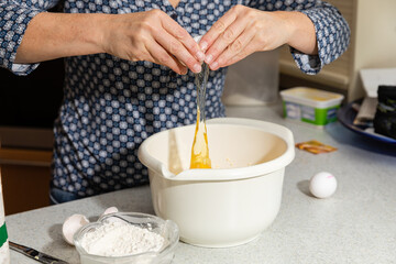 Obraz na płótnie Canvas Closeup of a person cracking an egg in a pot for cream in a kitchen