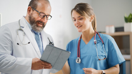 Doctor's Office: Physician Talks With Professional Head Nurse, Using Digital Tablet Computer....