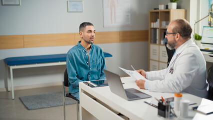 Hispanic Doctor Consultation Office: Male Patient Talks to Physician, Who Shows, and Explains Test Results. Health Care Professional Diagnosing Disease, Explaining Test Results, Prescribing Treatment