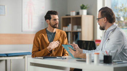 Doctor Consultation Office: Male Patient Describes Chest Pain to His Family Physician, Showing Where it Hurts. Friendly Medical Health Care Professional Uses Digital Tablet Computer to Enter Data.