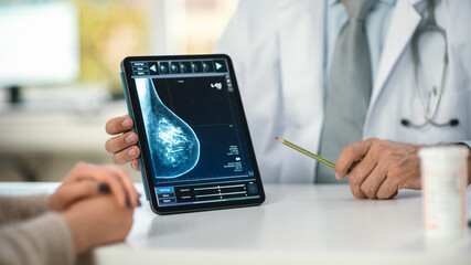 In a Doctor's Consultation Room: Friendly Professional Doctor Uses Digital Tablet Computer to Show...