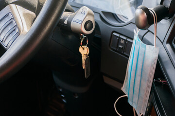 Surgical masks hanging from a truck's parking brake lever, with the ignition keys on.