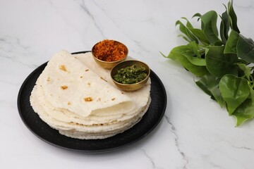 Rice bhakri, Chawal ki roti. It is a round soft flatbread. Usually eaten with fish, chicken or mutton thali. Served with garlic & green chutney. Copy space.