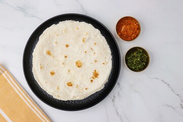 Rice bhakri, Chawal ki roti. It is a round soft flatbread. Usually eaten with fish, chicken or mutton thali. Served with garlic & green chutney. Copy space.