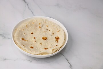 Rice bhakri, Chawal ki roti. It is a round soft flatbread. Usually eaten with fish, chicken or mutton thali. Served with garlic & green chutney. Copy space.