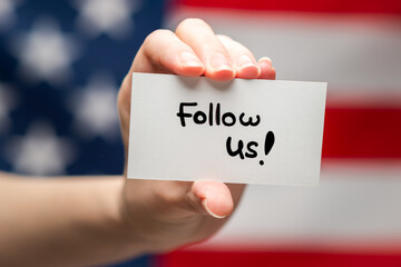Follow us text on a card. American flag background.