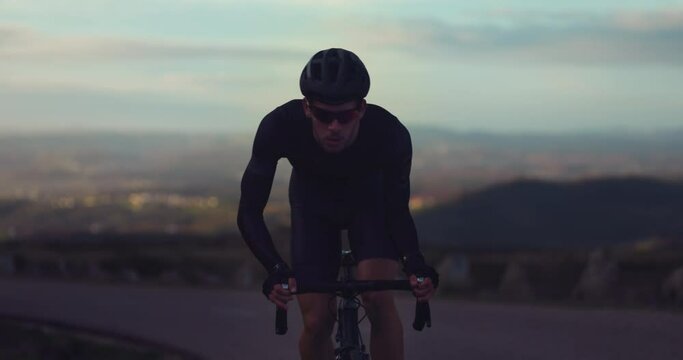 Professional cyclist riding bicycle on top of mountain at sunrise