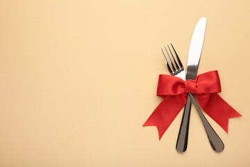 Fork and spoon with red ribbon on beige. Christmas setting