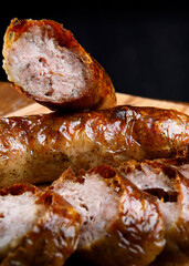 Cut home fried sausages on a wooden cutting board.
