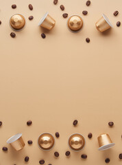 Caffeine, hot drinks and objects concept - close up of golden capsules or pods for coffee mashine with some roasted grains on beige background. Top view with space for text. Flat lay..