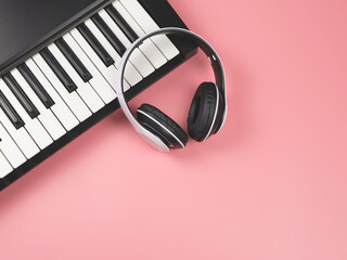 Obraz na płótnie Canvas flat lay of white headphones on electric piano on pink background with copy space.musician work set.