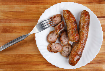 Homemade fried sausages in a white plate. Top view.