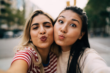 Close up portrait of Hispanic and Asian female friends making duck face and looking at camera...