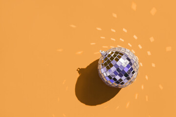 Christmas minimal festive background with christmas tree toy disco ball. Abstract glitter blurred background shiny color of the year orange marigold. Bright sparkling wallpaper with bokeh texture.
