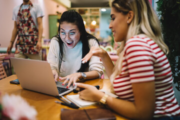 Amazed Asian hipster girl in trendy glasses shocked with received discount newsletter surprised with Black Friday shopping, female freelancer discussing projecting success during laptop browsing