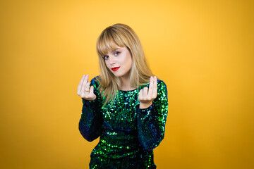 Beautiful blonde woman wearing a fancy dress over yellow background doing money gesture with hands, asking for salary payment, millionaire business