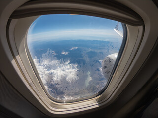 Pyrenees / Spain - March 11, 2020: Aerial view from airplane window on wing of Ryanair airlines and snow covered french and spanish pyrenees with snow covered mountains. Blue sky white clouds.