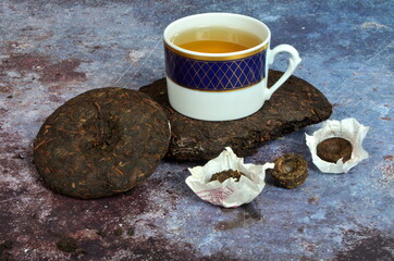 Cup of tea with various Chinese`s puer tea pancakes. Dry Chinese puer tea of high quality.
