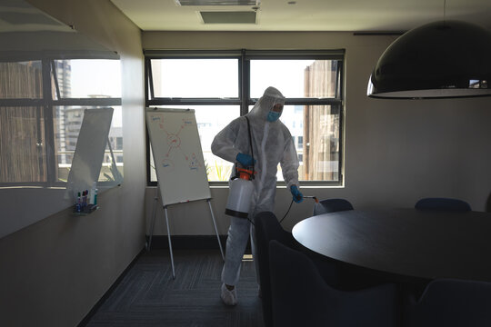 Health worker wearing protective clothes cleaning office using disinfectant