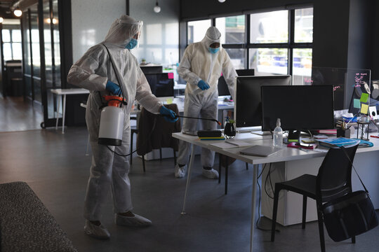 Team of health workers wearing protective clothes cleaning office using disinfectant