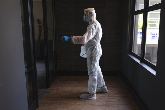 Health worker wearing protective clothes cleaning office using disinfectant