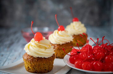 Homemade muffins and red cherries on white plates