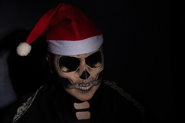 The death. Artistic makeup representing death in a game with a Santa Claus hat, Low Key image, selective focus.
