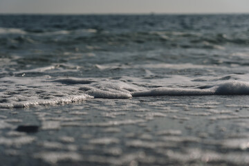 Fototapeta na wymiar Close up of sea foam on the sandy sea beach
