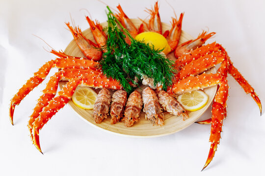 Red king crab and shrimp on a plate with lemon and dill. White background