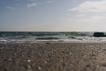 Closeup of wet stones in beach sand and wave