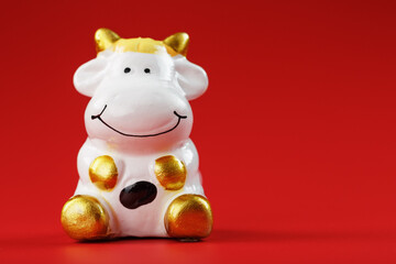 Naklejka premium Cow figurine on a red background, new year's concept. Free space.
