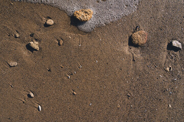 Closeup of wet stones in the sand on the beach