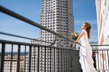 Beautiful blonde woman in a white dress walking on the balcony of a hotel in Madrid, Spain. On your wedding day before you get married.