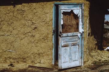 Old clay and hay house with broken door in a rural village of Moldova