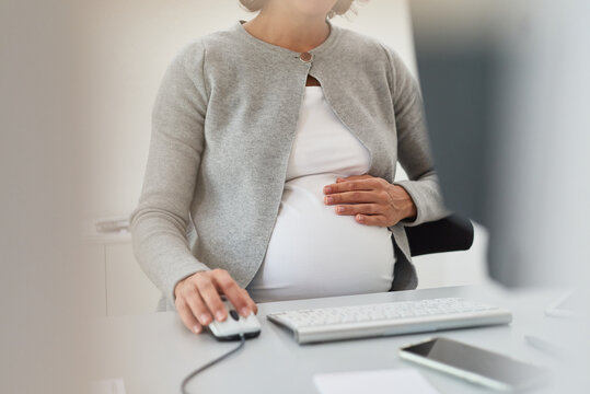 Schwangere Frau sitzt am Schreibtisch und arbeitet am Computer, Closeup