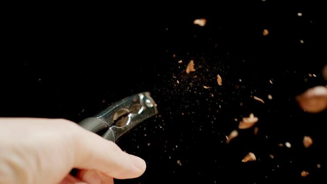 Man crushing a nut with a steel nutcracker. Slow motion.