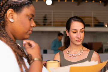 Charming business woman collaborating and discussing project plans in business cowork space. Partnership, teamwork, collaboration concept..
